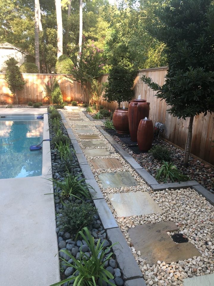 Luxury pool side landscaping with travertine deck, tropical plants, and LED lighting in The Woodlands, TX